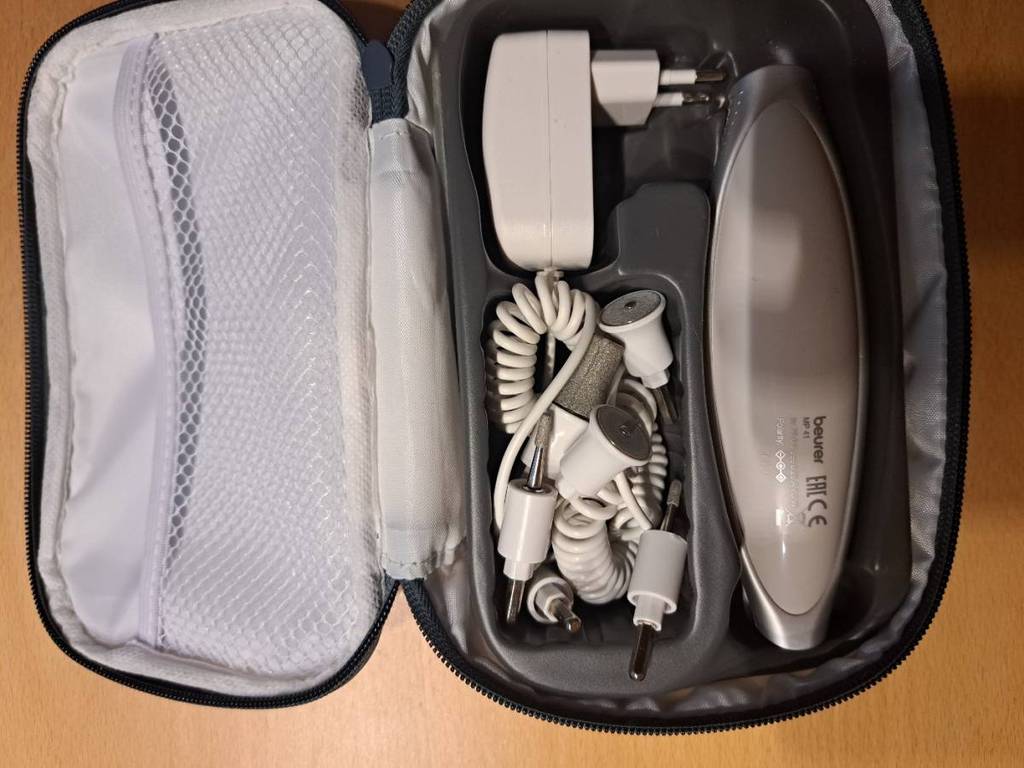 Nahaufnahme der geöffneten Aufbewahrungstasche eines Gerätes eines Maniküre-Sets mit mehreren Aufsätzen und Adapter.
