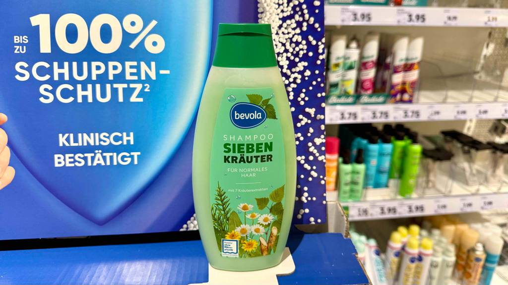 Getestet: Kräuter-Shampoo steht auf einem Karton vor einem Verkaufsregal mit Kosmetikprodukten im Drogeriemarkt.