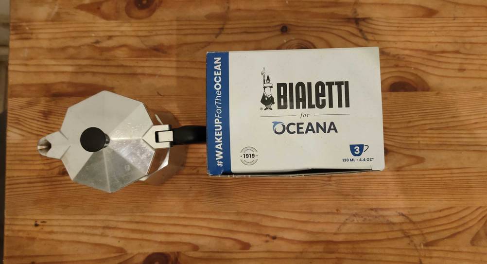 Eine getestete Bialetti neben ihrer Originalverpackung auf einer Holzfläche.