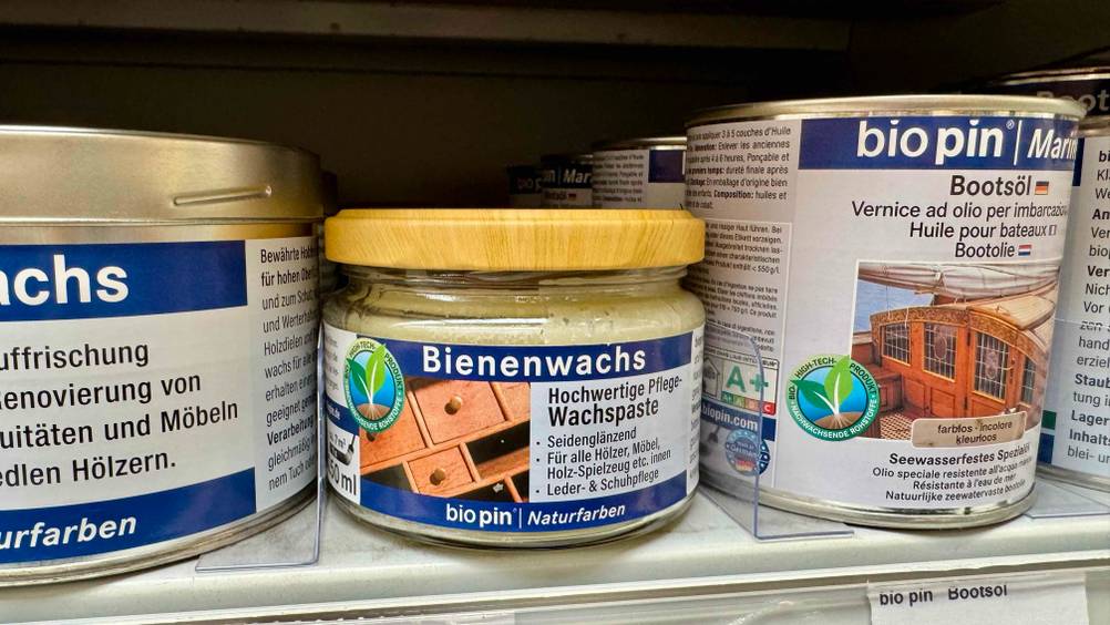 Mehrere Dosen des getesteten Bienenwachs in einem Verkaufsregal neben anderen Produkten.
