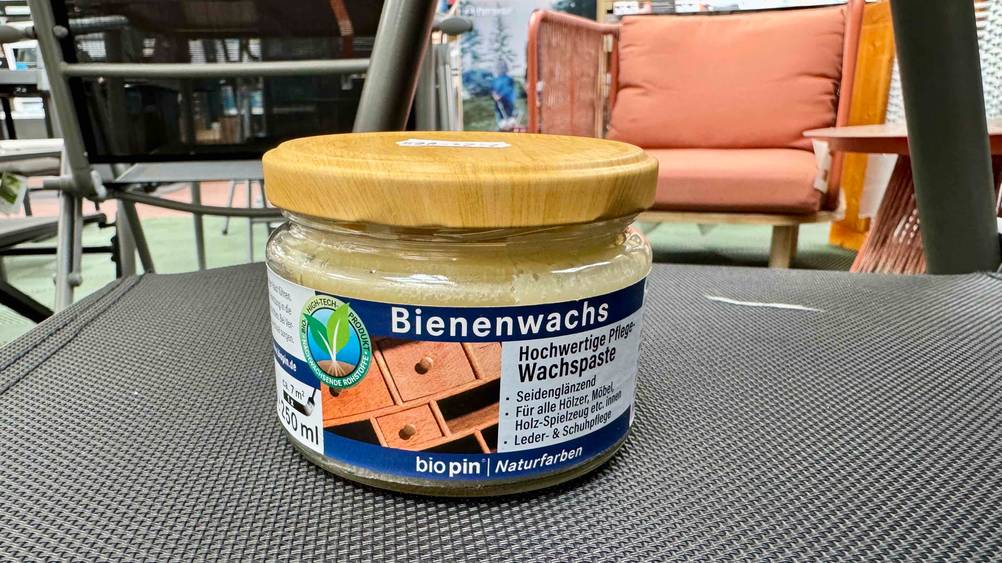 Das getestete Bienenwachs steht auf einem Stuhl, im Hintergrund Outdoormöbel.