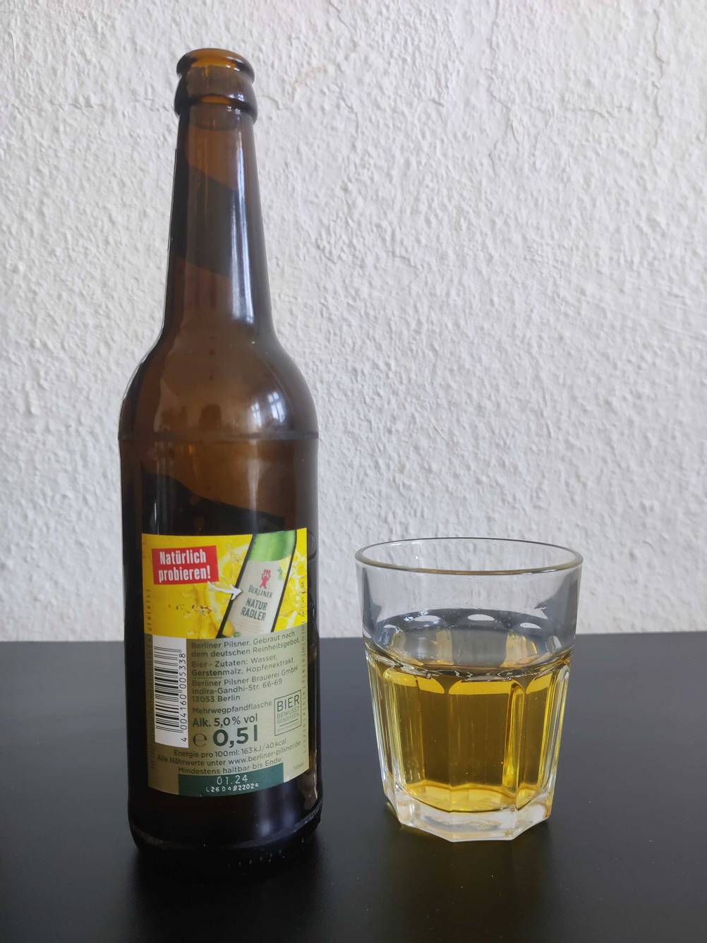 Bio-Honig getestet: Eine Flasche mit der Rückseite nach vorne neben einem Glas.