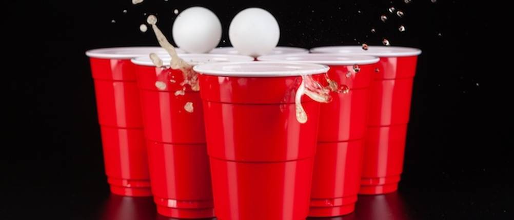 Bier-Pong-Tisch im Test: Rote Becher, Bierschaum und zwei Tischtennisbälle in Nahaufnahme.