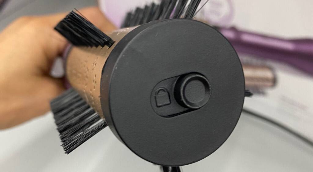 BaByliss-Warmluftbürsten im Test: Nahaufnahme des schwarzen Kopfendes der Rundbürste inklusive Feststellknopf.