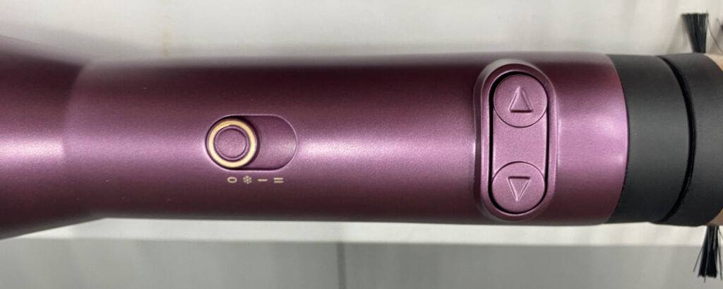 BaByliss-Warmluftbürsten-Test: Nahaufnahme des violettfarbenen Griffs mit Einstelltaste und Richtungsregler.