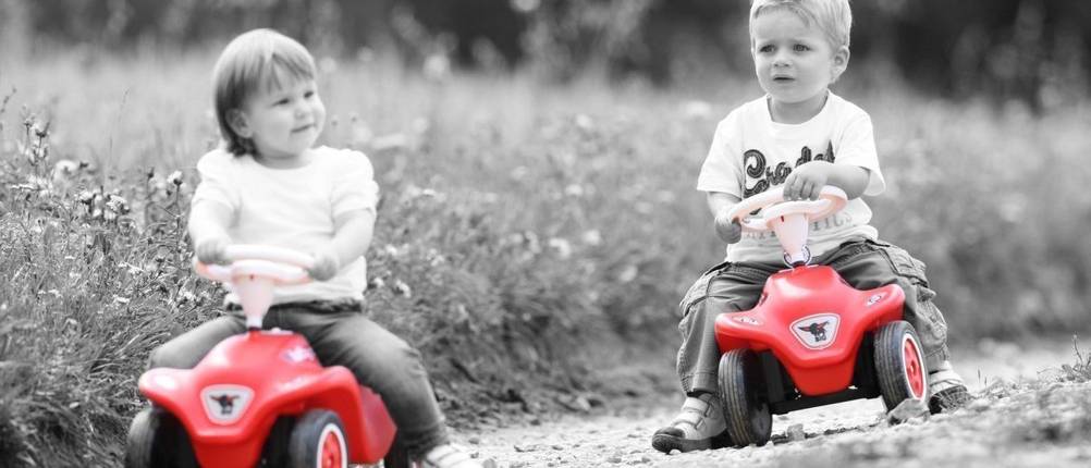 Bobby-Car im Test: Zwei Kinder die mit ihren Bobby-Cars auf einem Feldweg unterwegs sind.