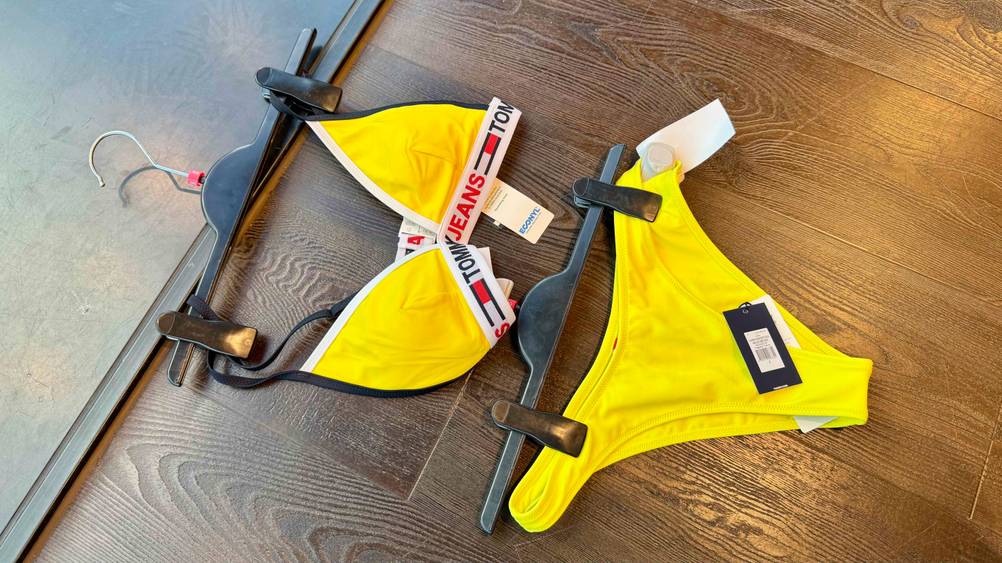 Ein getesteter gelber Bikini liegt auf einem Holzboden.