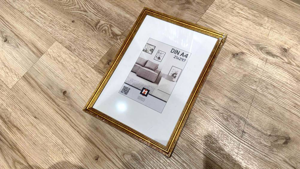 Ein getesteter Bilderrahmen liegt auf einem Holzboden.