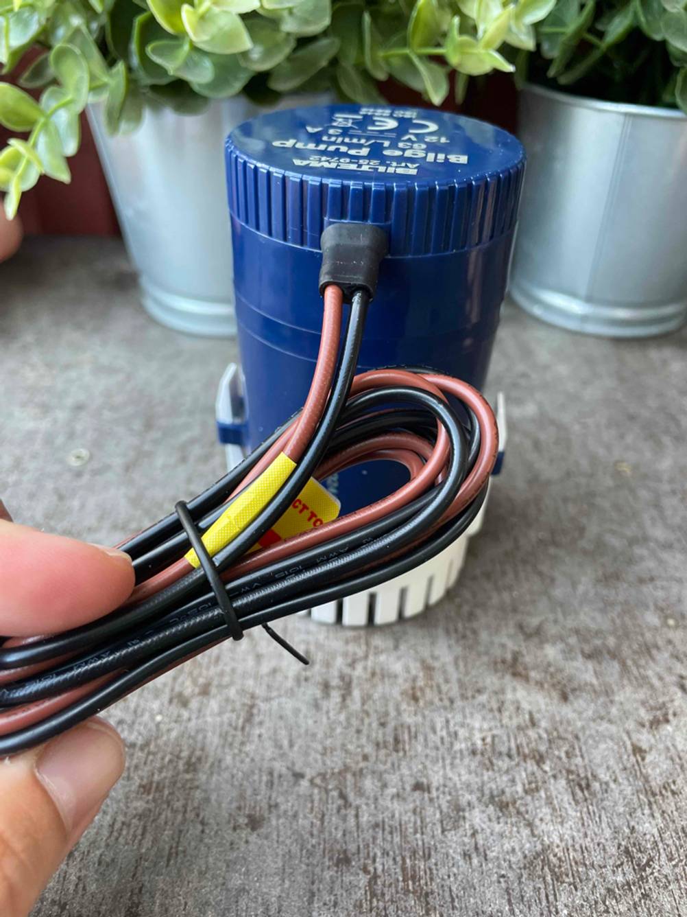 Bilgenpumpe getestet: Eine Hand hält die Kabel einer Bilgenpumpe.