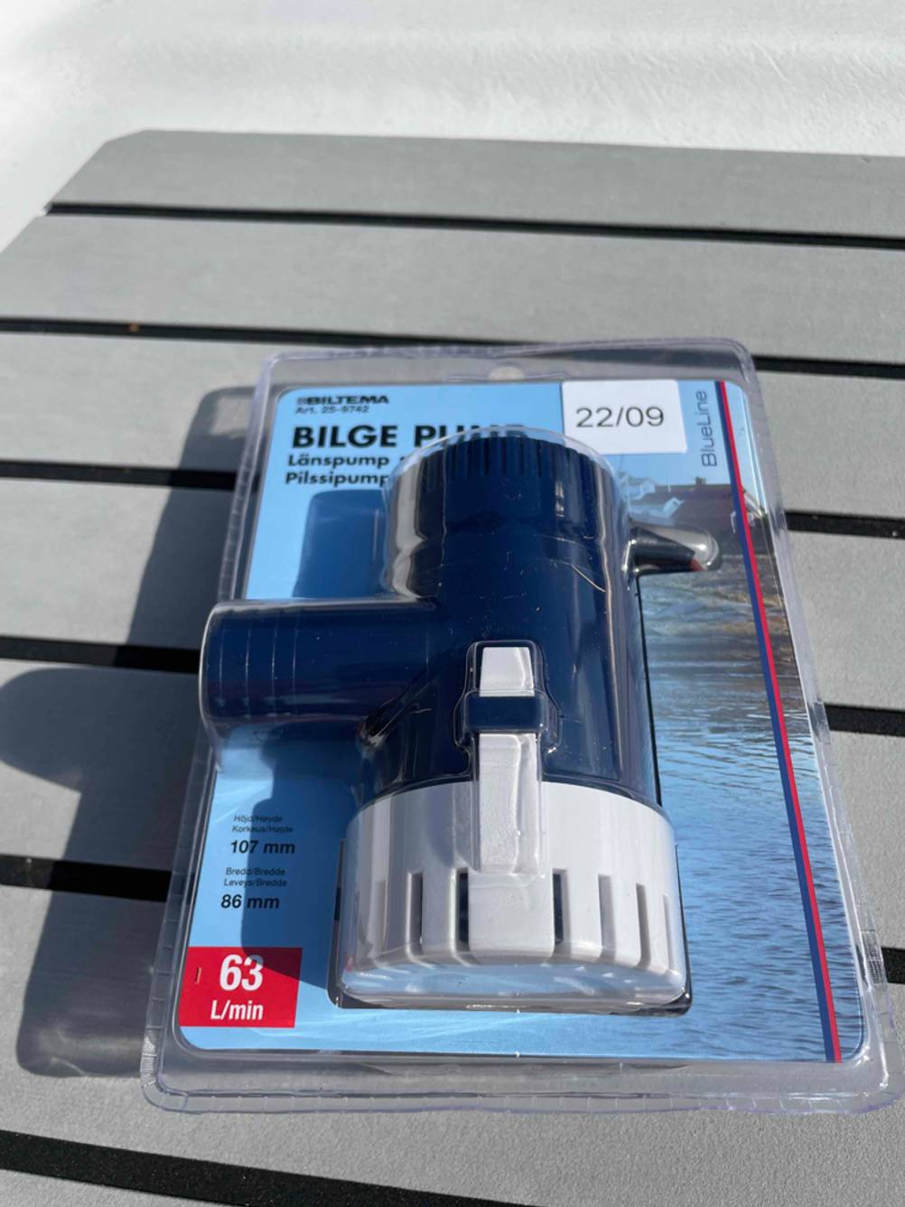 Bilgenpumpe im Test: eine verpackte Pumpe liegt auf Metalllamellen.