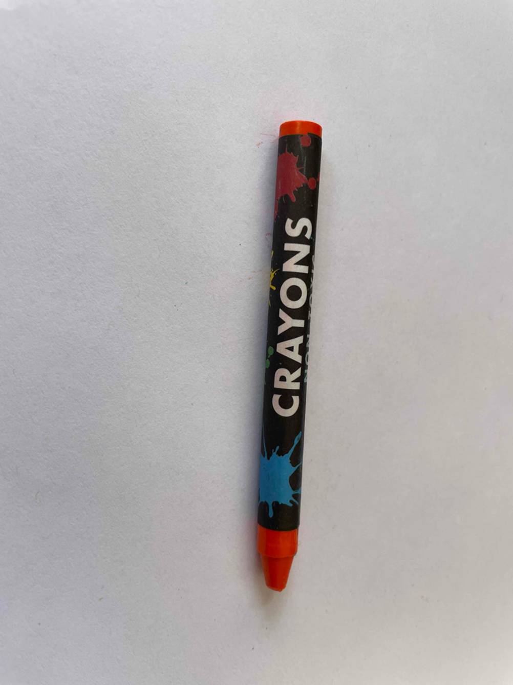 Ein getesteter Crayons Wachsmalstift in rot liegt auf einer weißen Fläche.