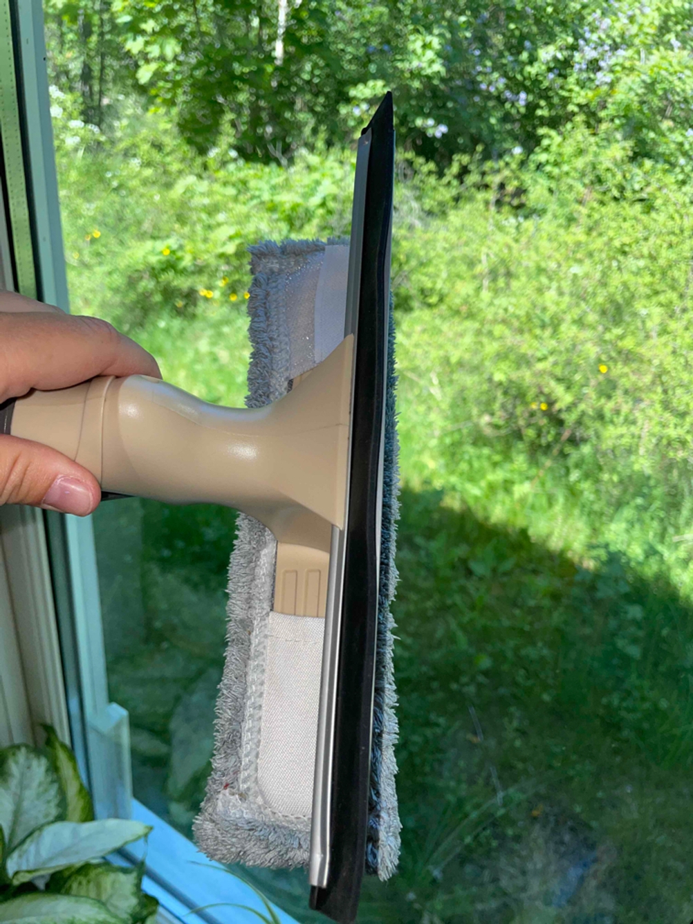 Fensterwischer-Test: Eine Person reinigt mit einem Fensterwischer mit Gummilippe ein Fenster