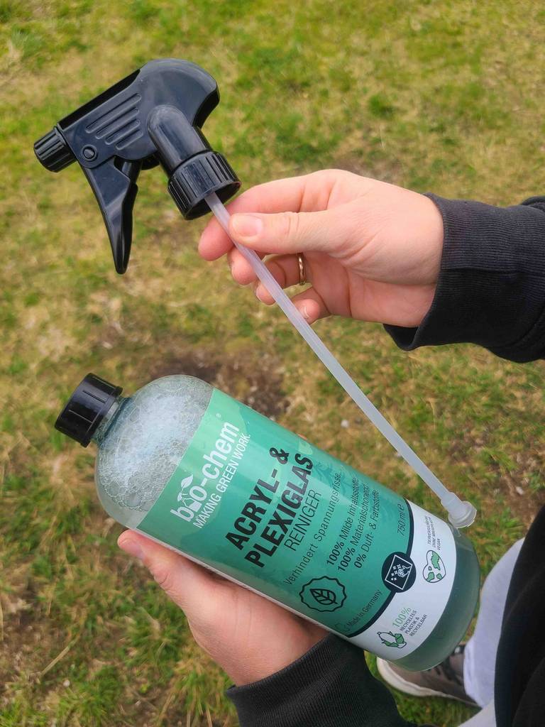 Kunststofffenster-Reiniger-Test: Eine Hand hält die Flasche, die andere hält Schlauch mit Sprühkopf.