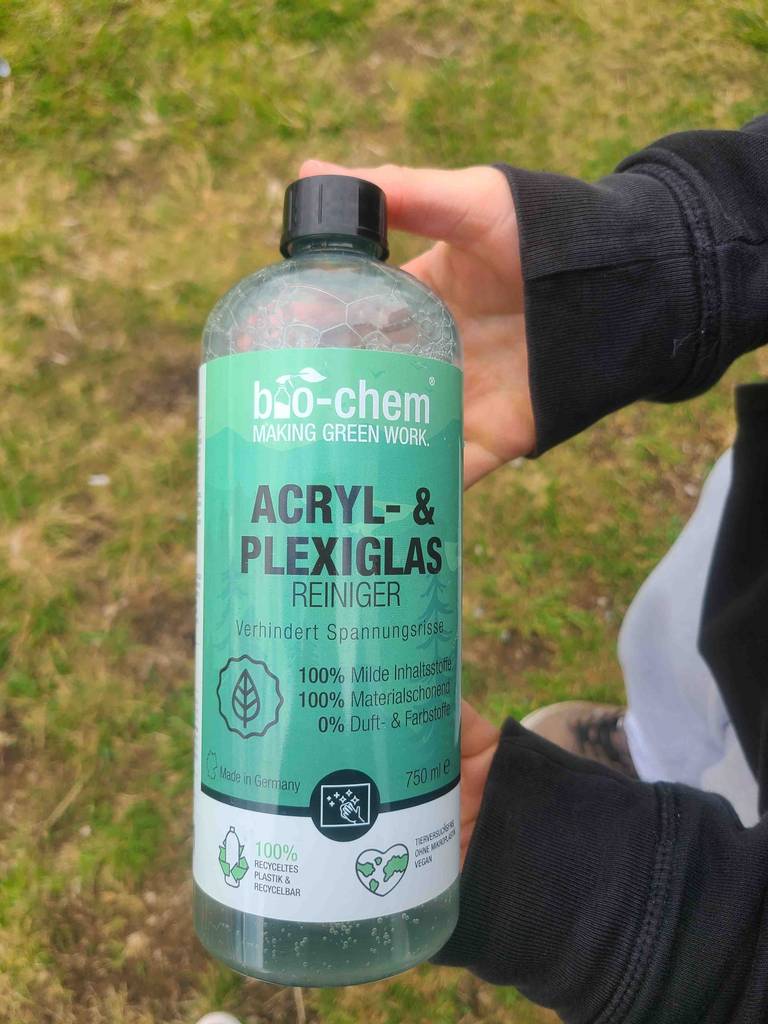Im Test: Eine Hand hält eine Flasche Kunststofffenster-Reiniger.