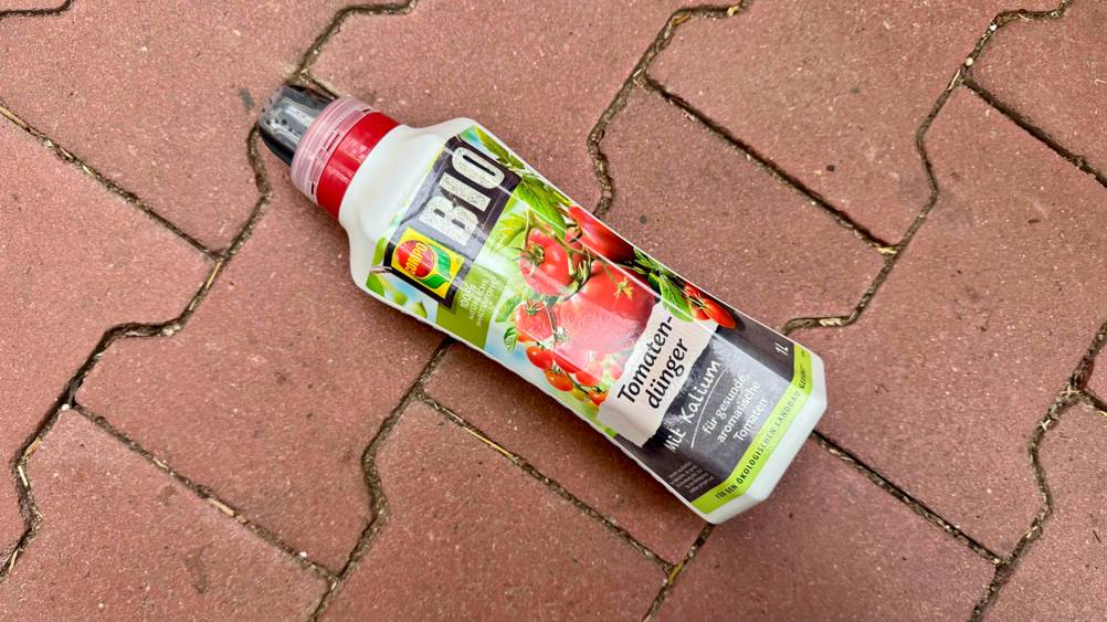 Auf einem Pflasterboden liegt eine Flasche des Bio-Dünger flüssig horizontal.