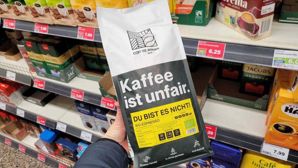 Eine Hand hält eine Packung des getesteten Bio-Fairtrade-Kaffees vor ein Regal.