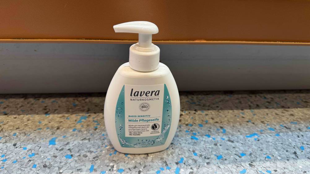 Bio-Flüssigseife im Test: Eine Flasche von schräg oben vor einer orangen Wand.