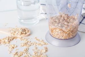 Bio-Haferflocken-Test: In einem Mixer befinden sich eingeweichte Haferflocken. Daneben liegt ein Holzlöffel mit Haferflocken. 