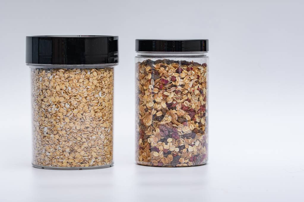 Bio-Haferflocken-Test: Zwei wiederverschließbare Dosen mit Haferflocken und Müsli stehen auf einer hellen Oberfläche. 