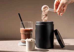 Bio-Hanfprotein-Test: Eine Person streut Proteinpulver in einen Becher-to-go. 