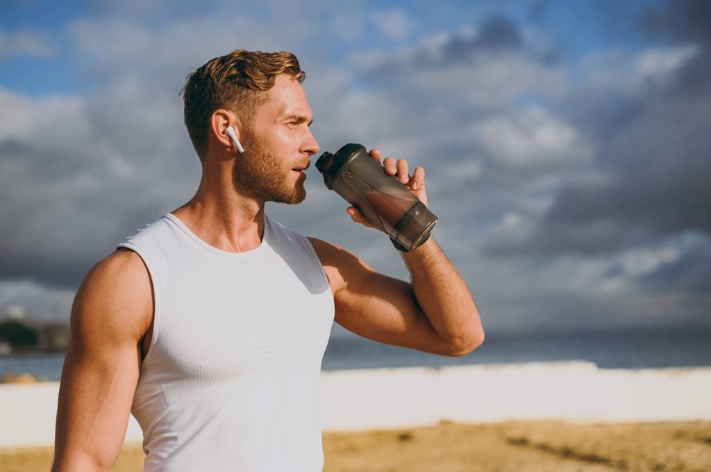 Bio-Hanfprotein-Test: Ein Mann in Sportbekleidung blickt in die Ferne und trinkt einen Proteinshake. 