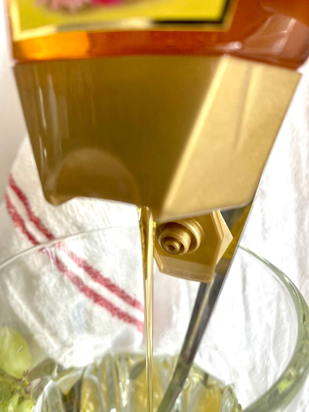 Nahaufnahme des Dosierkopfes eines getesteten Bio-Honigs der in ein Glas gegeben wird.