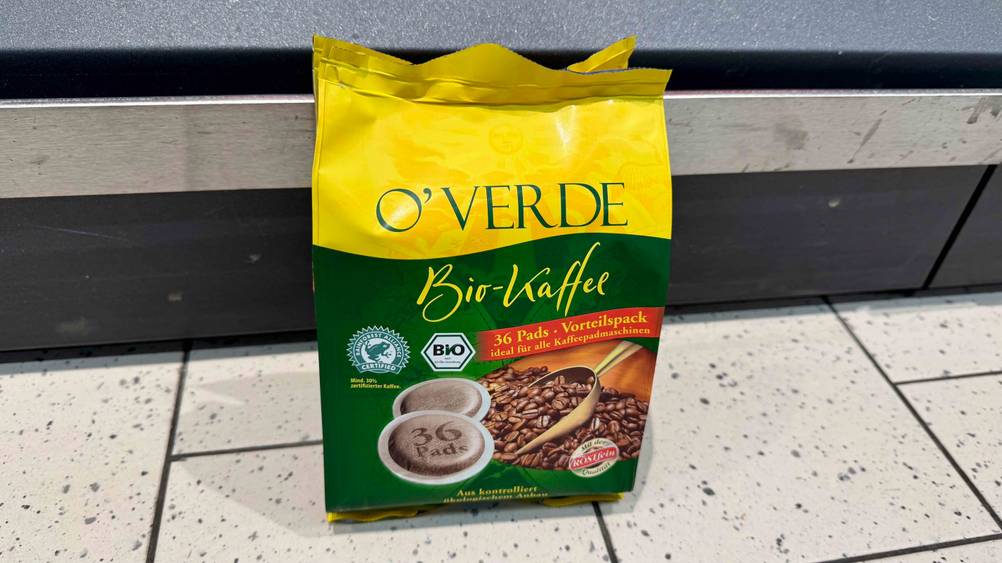 Eine Packung der getesteten Bio-Kaffeepads von vorne auf einem hellen Boden stehend.