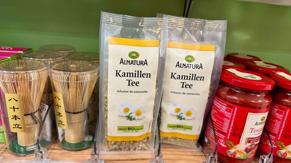 Mehrere Packungen des getesteten Bio-Kamillentees in einem Verkaufsregal neben anderen Produkten.