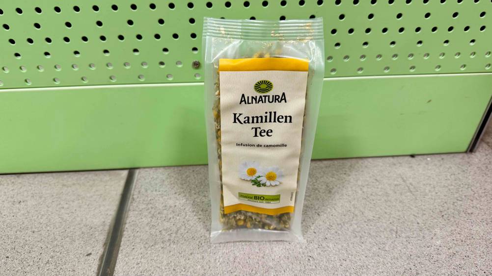 Eine Packung des Bio-Kamillentee im Test vor einer grünen Wand auf dem Boden stehend.