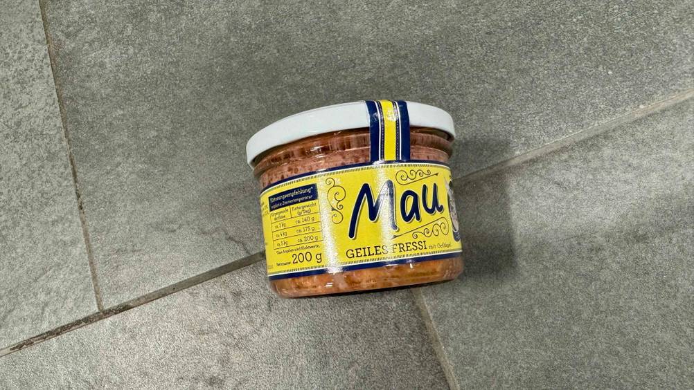 Auf einem grauen Boden liegt ein Glas Bio-Katzenfutter im Test.