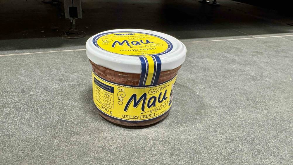 Ein Glas des getesteten Bio-Katzenfutters auf einem grauen Boden stehend.