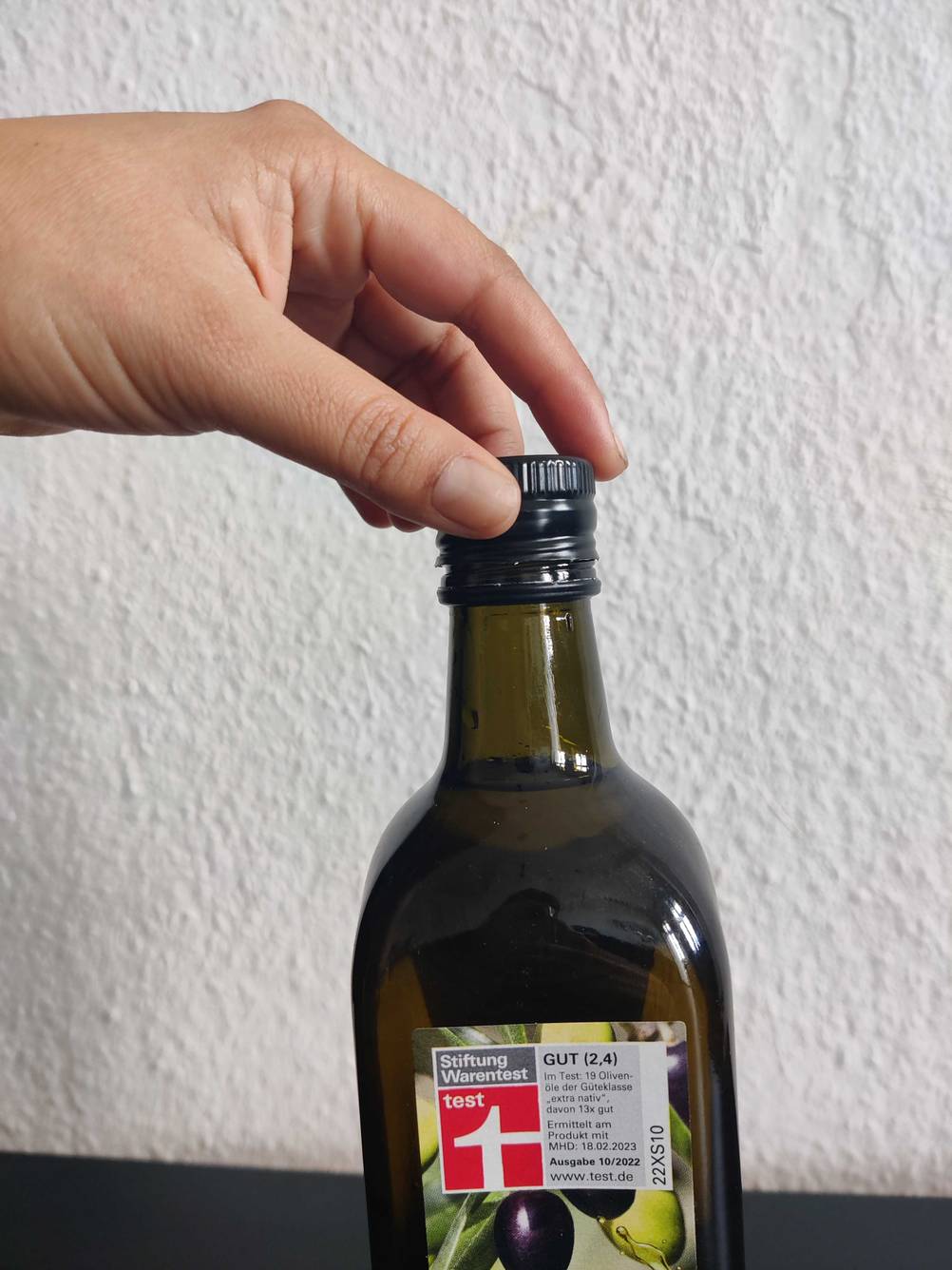Eine Hand verschließt eine Flasche des getesteten Bio-Olivenöls.