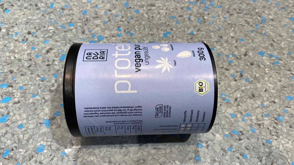 Auf dem Boden befindet sich eine Packung getestetes Bio-Proteinpulver.