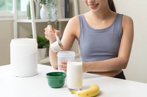 Bio-Proteinpulver-Test: Eine Frau steht in der Küche und bereitet einen Proteinshake zu. 