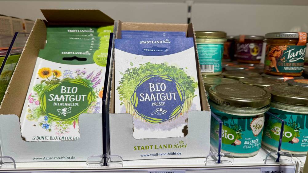 Mehrere Packungen des Bio-Saatgutes im Test in einem Verkaufsregal neben anderen Produkten.