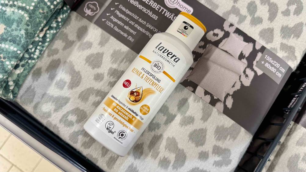 Auf einer verpackten Bettwäsche liegt eine Flasche Bio-Shampoo im Test.