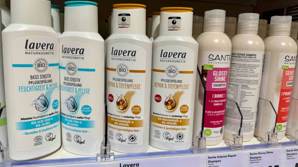 Mehrere Flaschen des getesteten Bio-Shampoos neben anderen Produkten in einem Regal.