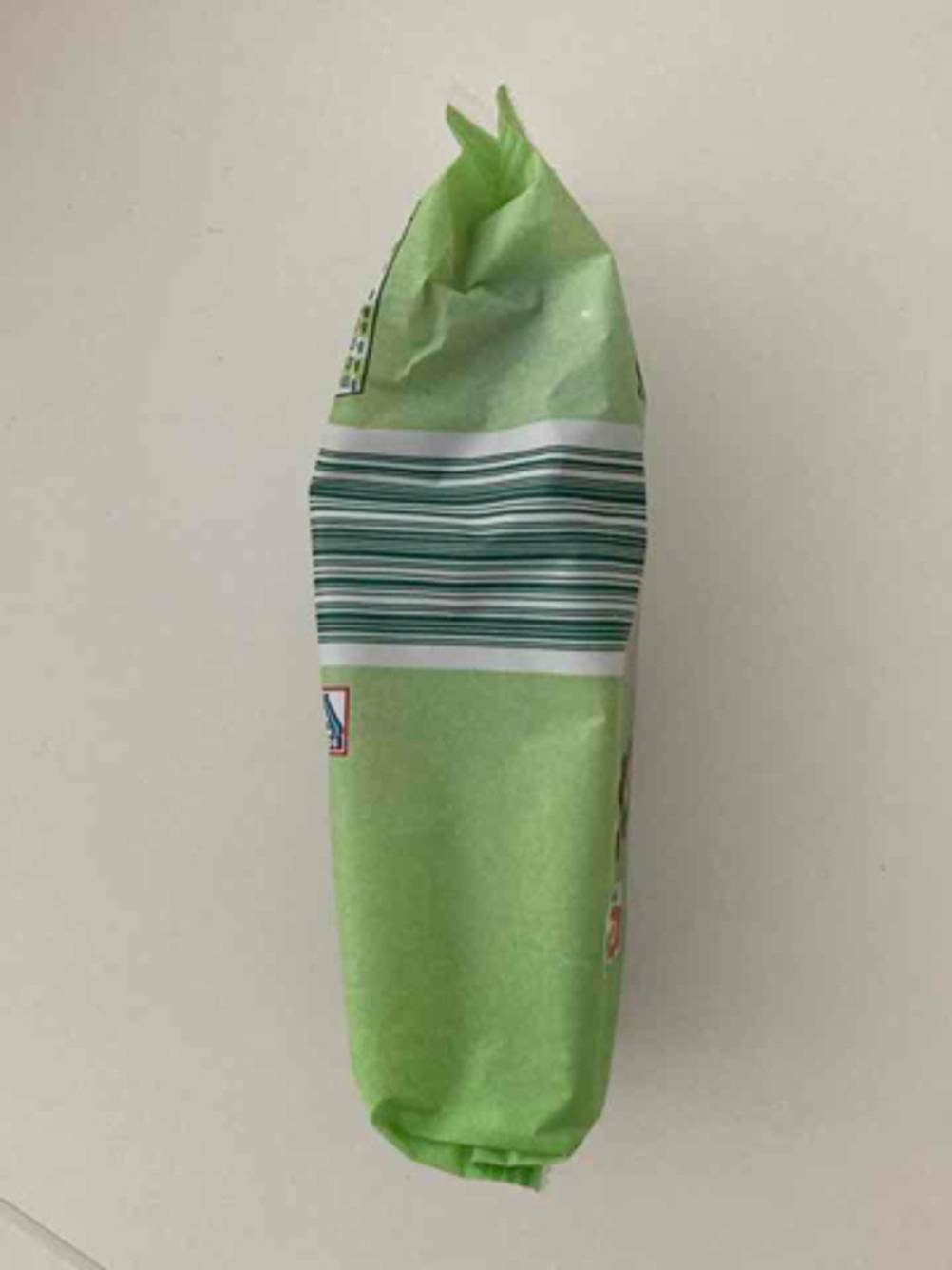Seitenansicht einer grünen Packung getrockneter Früchte im Test auf einer weißen Oberfläche.