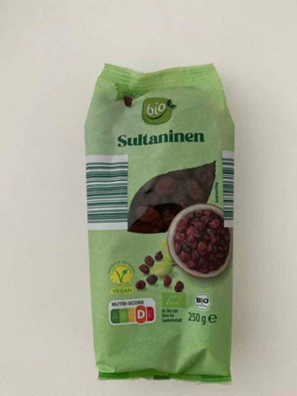 Eine grüne 250-g-Packung, inklusive Sichtfenster, mit getesteten, getrockneten Früchten liegt auf einer weißen Oberfläche.