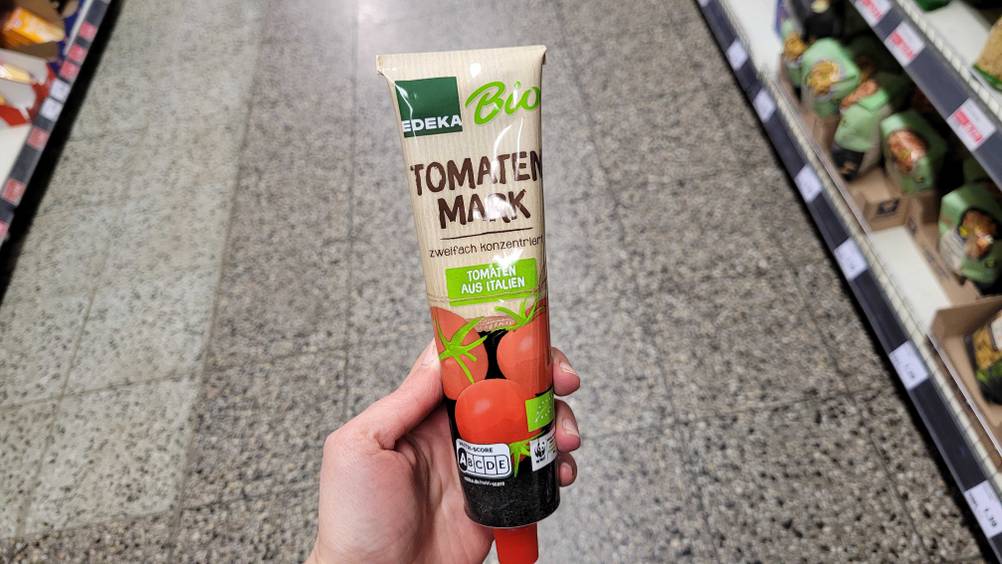 Eine Hand hält eine Tube des getesteten Bio-Tomatenmarks.