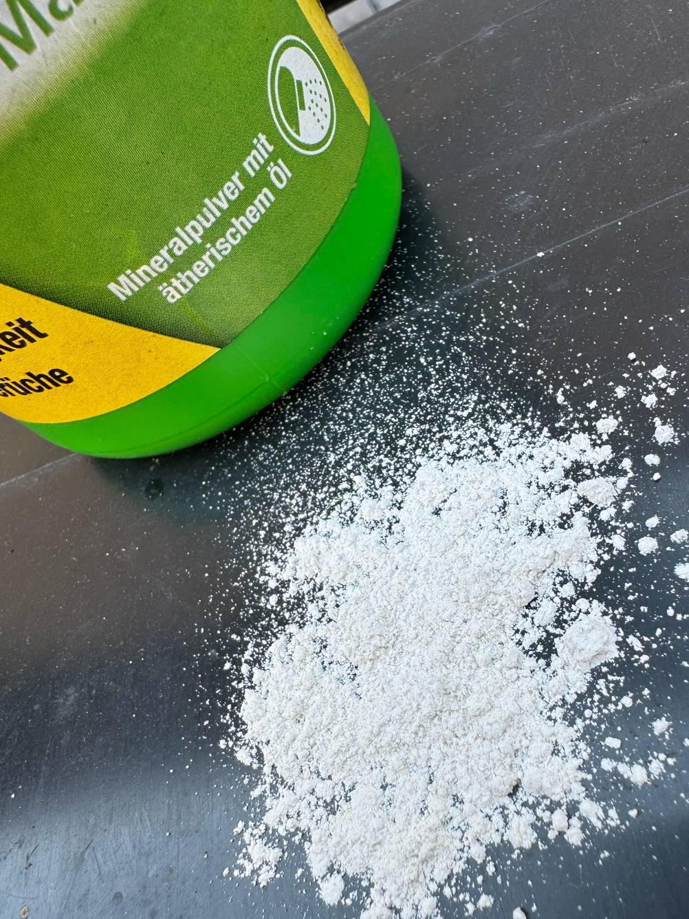Auf einer schwarzen Fläche ist vor einer Flasche ein kleines Häufchen Biotonnenpulver zum Testen.