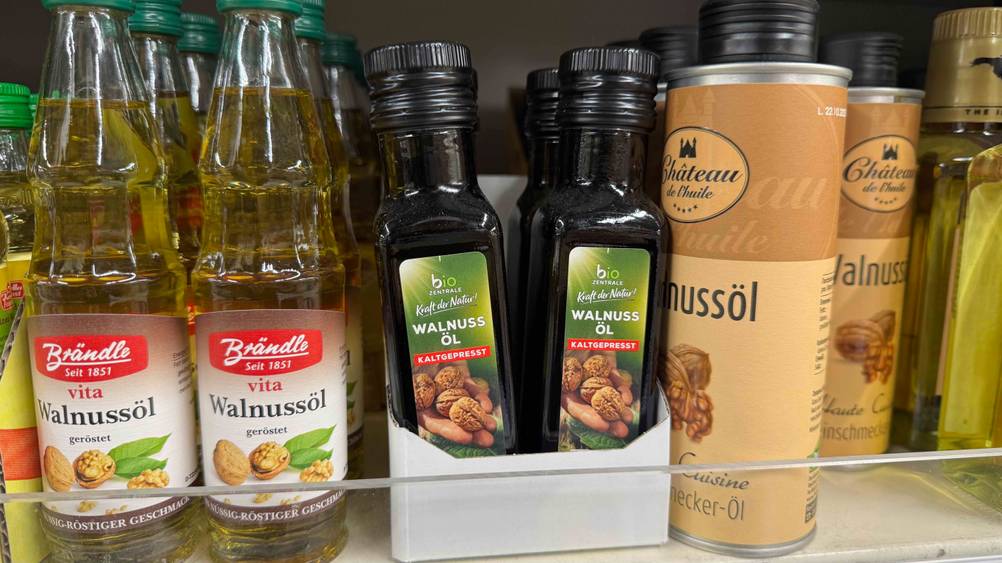 Mehrere Flaschen des getesteten Bio-Walnussöls in einem Verkaufsregal neben anderen Produkten.