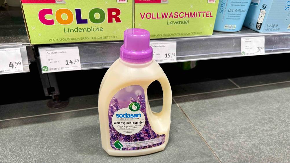 Vor einem Verkaufsregal auf dem Boden steht eine Flasche des Bio-Weichspüler im Test.