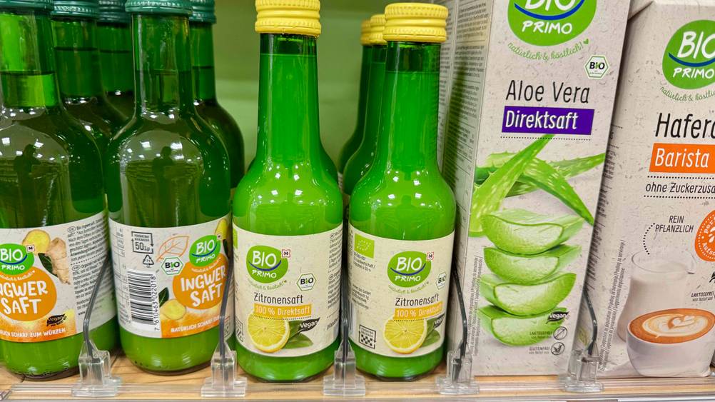 Mehrere Flaschen des Bio-Zitronensaft im Test in einem Verkaufsregal neben anderen Produkten.