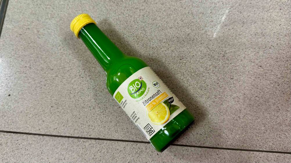 Bio-Zitronensaft im Test: Eine Flasche liegt auf einem Fließenboden.