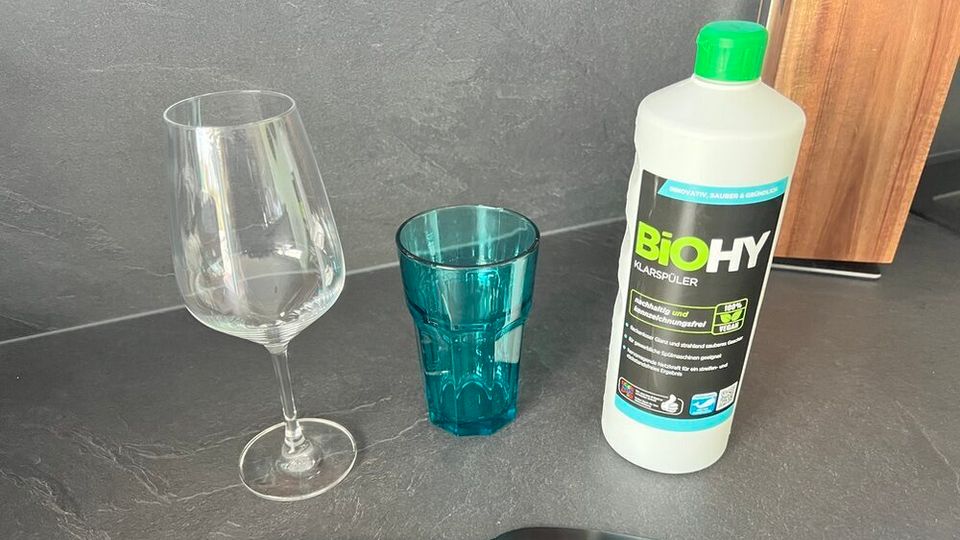 Der Biohy Klarspüler steht neben einem Weinglas, einem Glas und einem Messer