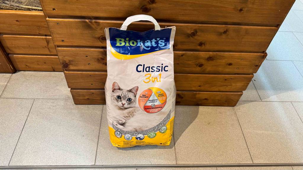 Ein Sack getestetes Biokats Katzenstreu steht vor einem Holzkasten.