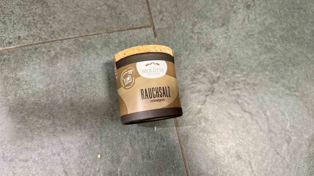 Rauchsalz im Test: Eine Gewürzdose mit körnigem Salz liegt auf einer grauen Oberfläche.