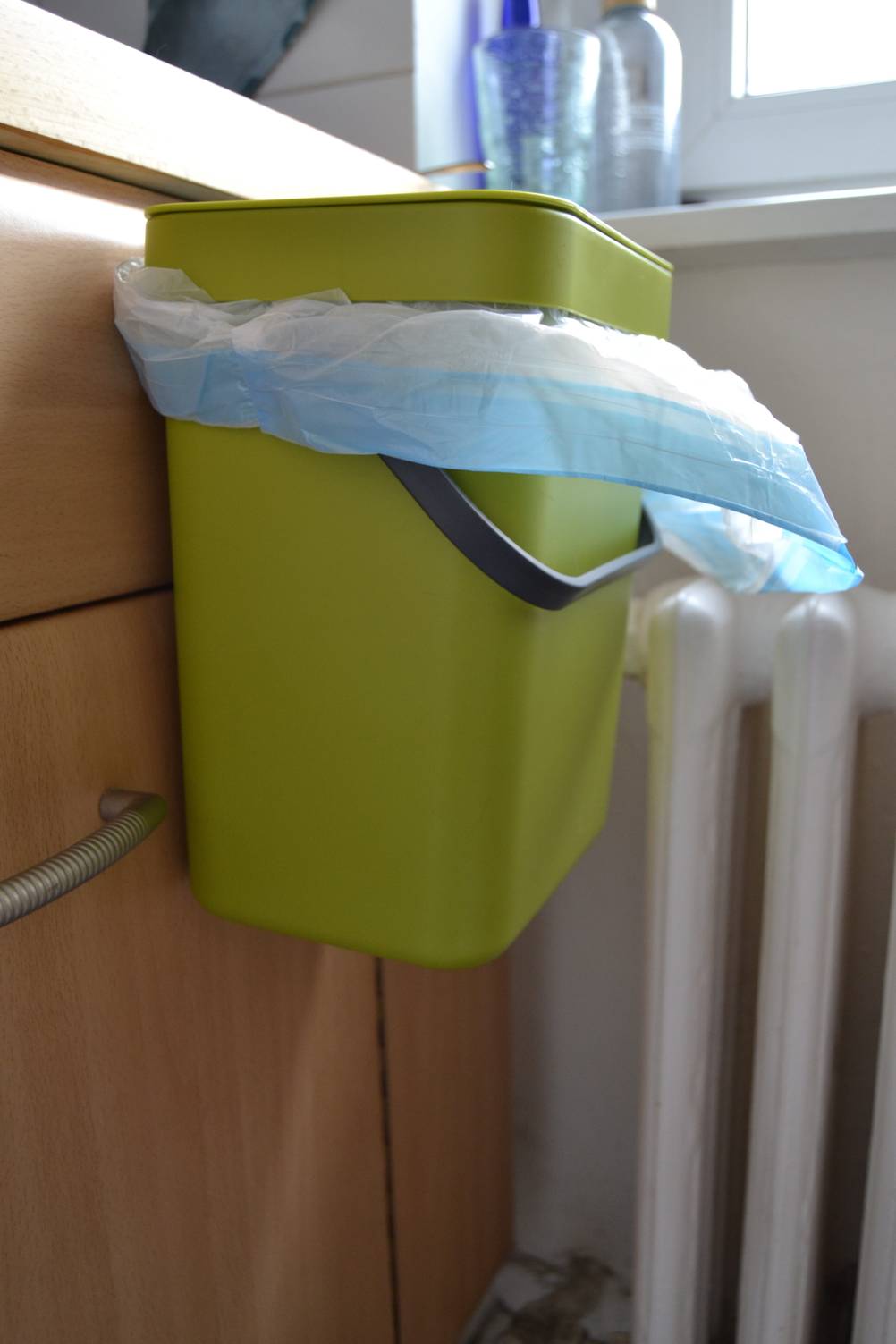Ein getesteter grüner Biomülleimer an einer Küchentüre festgemacht.