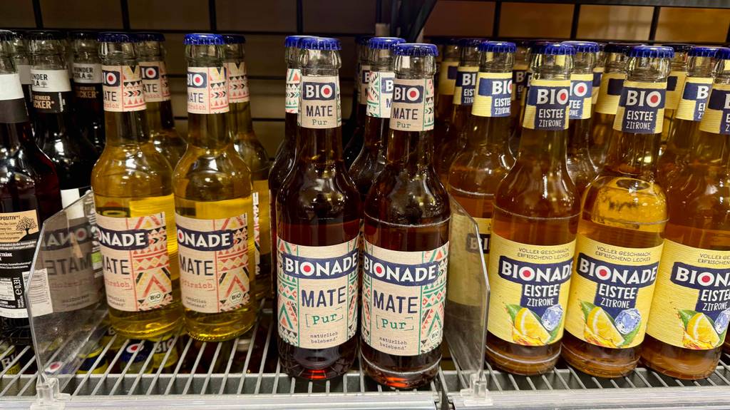 Im Test: Bio-Mate Tee in der Flasche steht inmitten anderer Getränkeflaschen in einem Verkaufsregal.